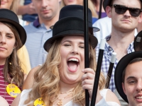 A female student wearing a black hat and holding a cane smiles