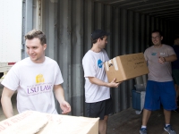 Male students handle boxes of clothing around a warehouse