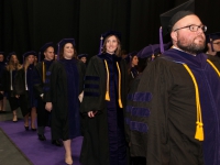 Students wearing graduation attire smile
