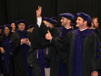 Students wearing graduation attire smile