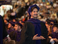 A student wearing graduation attire smiles