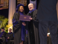 A man and a student wearing graduation attire pose for a photo