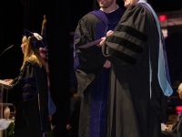A man and a student wearing graduation attire pose for a photo