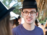A male student wearing a black hat looks on