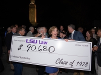A woman holds a large check for $90,680 with the Louisiana state capitol in the background.