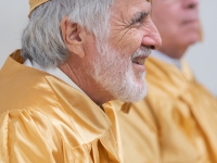 A man wearing a gold robe smiles