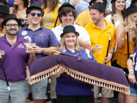 A woman holds a pillow with a black and gold cane in front of a group of people