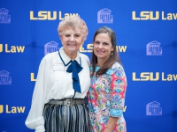 A female student and a woman pose for a photo with the LSU Law logo in the background