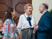 A woman smiles as she talks to a man and a woman
