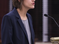 A female student wearing a suit speaks at a podium
