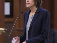 A female student wearing a suit speaks at a podium