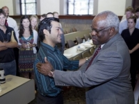 A man wearing a suit shakes hands with a student