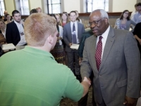 A man wearing a suit shakes hands with a student